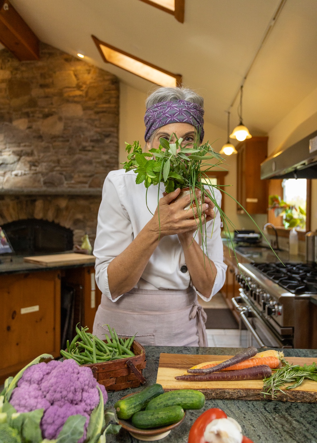 Cathy in a kitchen with a bunch of herbs